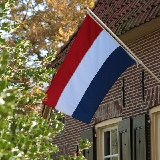 Wapperende vlag aan boerderijgevel.